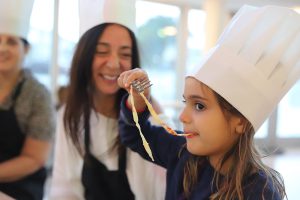 Happy daughter eating pasta at Mommy and Me class